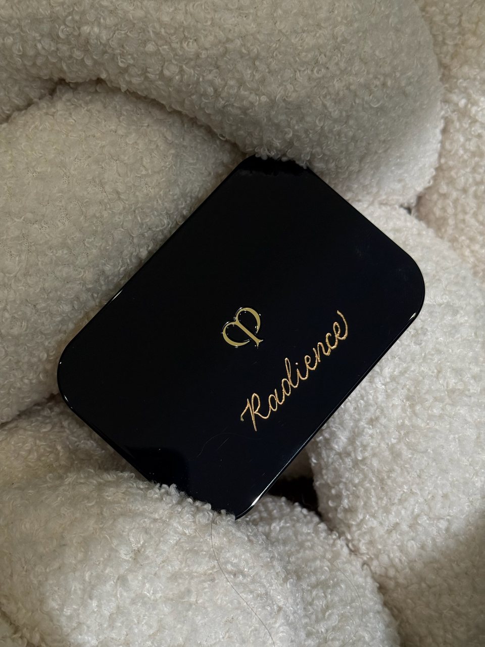 Clé de Peau Beauté black compact with gold CP logo and calligraphed name